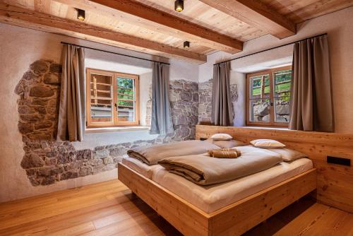 a bedroom with a large bed and two windows at Egger an der Lahn - Apt Nonna in San Genesio Atesino