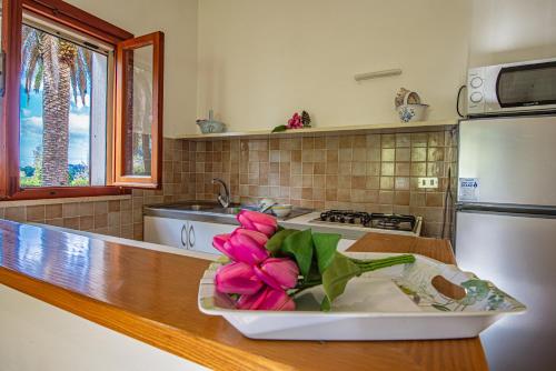 a kitchen with pink flowers in a bowl on a counter at Villa Vanna Bilo A - bilocale in Capoliveri