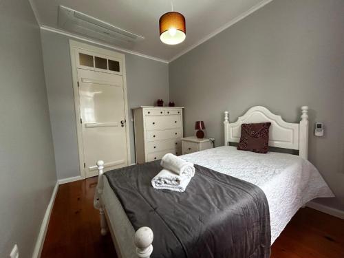 a bedroom with a white bed and a dresser at Desterro House in Angra do Heroísmo