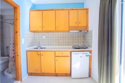 a kitchen with yellow cabinets and a white refrigerator at Nidri view Apartments in Nydri