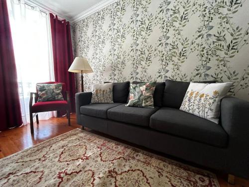 a living room with a black couch and a red chair at Desterro House in Angra do Heroísmo