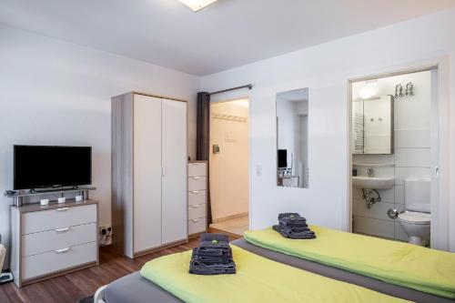 a bedroom with two beds and a tv and a bathroom at Schwarzwaldblick F App 3 mit Pool in Schönwald