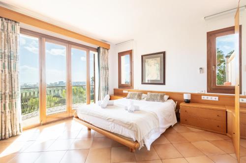a bedroom with a large bed and large windows at Villas2meet Na Penyal 7 in Cala Millor