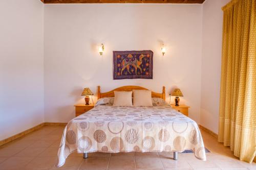 a bedroom with a bed and two lamps and a painting on the wall at Can Consul in San Juan Bautista