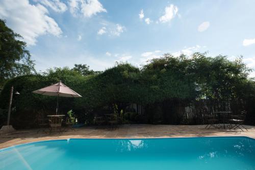 a swimming pool with an umbrella and chairs and tables at Pousada da Bia in Tiradentes