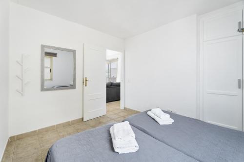 a white bedroom with two beds and a mirror at Turandot 34 La Restinga in La Restinga