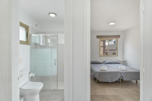 a white bedroom with a bed and a bathroom at Turandot 34 La Restinga in La Restinga