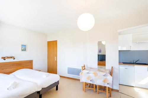 a room with two beds and a table and a kitchen at Les Mimosas - Appartement 08 in Cazaubon