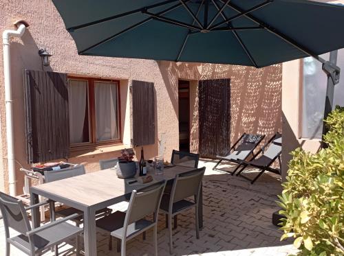 a table and chairs with an umbrella on a patio at Gîte Capibay Les Herbes de Provence in Six-Fours-les-Plages