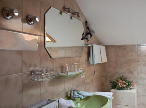a bathroom with a green sink and a mirror at Landhaus Reiser in Grainau