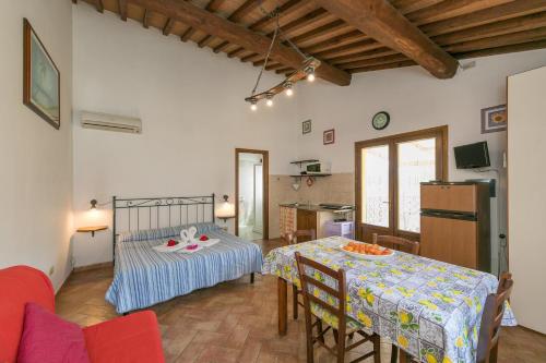 a bedroom with a bed and a table and a kitchen at Il Pino - monolocale Lavanda in Cecina
