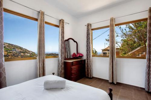 a bedroom with a bed and two large windows at Pico The Best View in Ribeira Brava