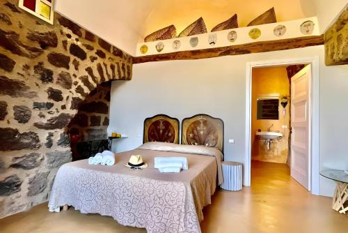 a bedroom with a bed and a stone wall at Dammuso Civulia Pantelleria in Pantelleria