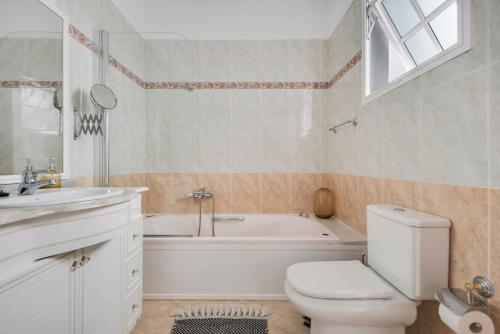 a bathroom with a toilet and a tub and a sink at Casa Alba in Lomo de Arico