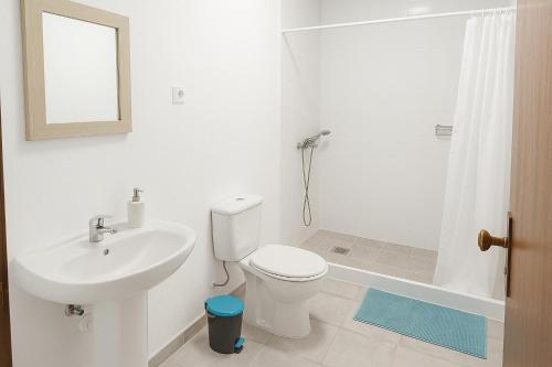 a white bathroom with a toilet and a sink at apartment near the airport in Ponta Delgada