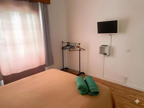 a bedroom with a bed with two green pillows on it at apartment near the airport in Ponta Delgada