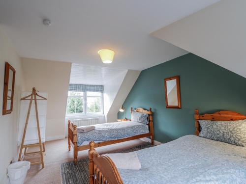 a bedroom with two beds and a green wall at Achnagonlin House in Grantown on Spey