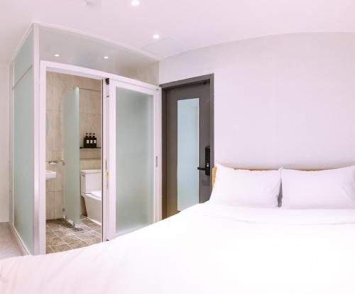 a white bedroom with a bed and a bathroom at D-Haus Hostel Dongdaemun in Seoul