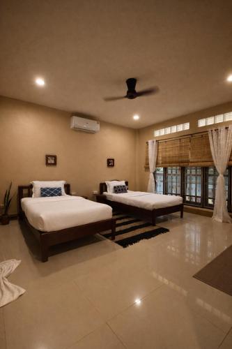 a bedroom with two beds and a ceiling fan at Lilo House, Thaimueang Beach in Thai Muang