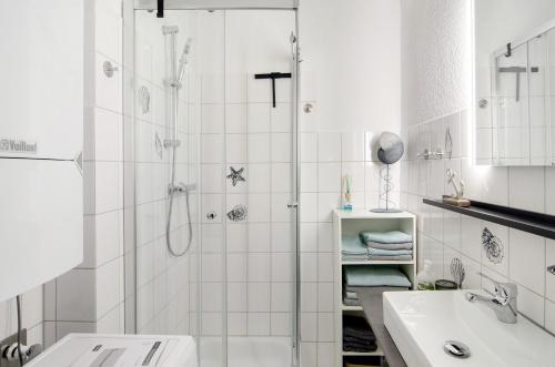a white bathroom with a shower and a sink at Ferienwohnung City in Emden
