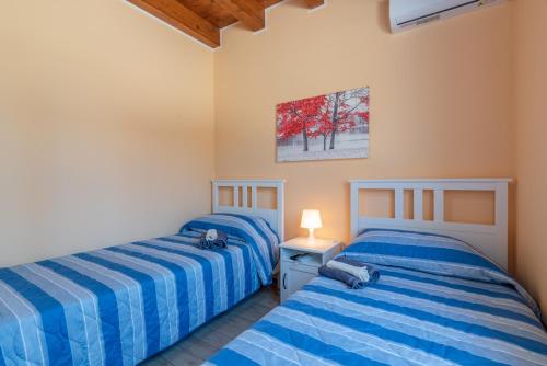 two beds in a bedroom with blue striped sheets at Casa Vacanza Brucoli Mare 2 in Brucoli