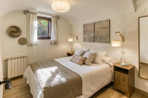 a bedroom with a large white bed and a window at El Celler - Can Bonet in Sant Martí Vell