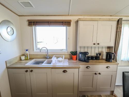 a small kitchen with a sink and a window at Number 6 - Sandy Beach Holiday Park in Norwich