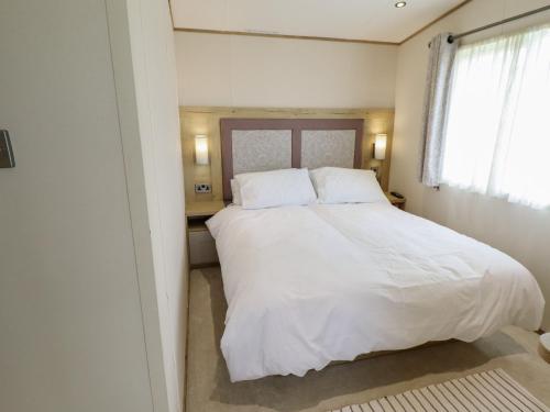 a bedroom with a large bed with white sheets and pillows at Number 6 - Sandy Beach Holiday Park in Norwich
