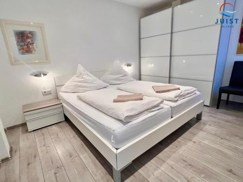 a bedroom with a white bed with white sheets at Haus Insa 145 - Ferienwohnung elf in Juist