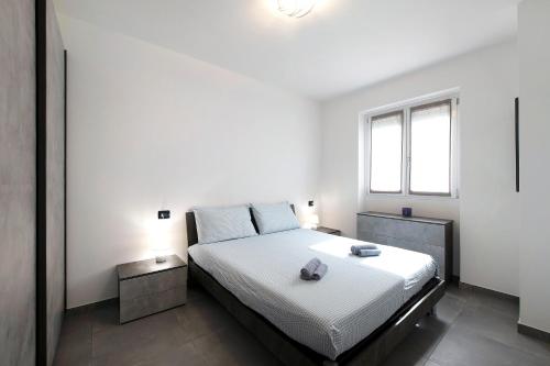 a bedroom with a bed with white sheets and a window at Appartamento 8 Il Tornante in Nesso