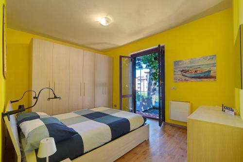 a bedroom with yellow walls and a bed and a window at Casa Sole e Mare in Arenzano