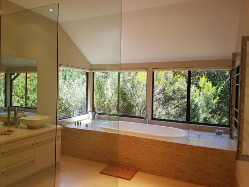 a large bathroom with a large tub and windows at Jarrah Grove Forest Retreat in Rosa Glen
