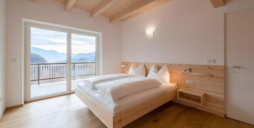 a bedroom with a bed and a large window at Kardonighof Kaltern in Caldaro