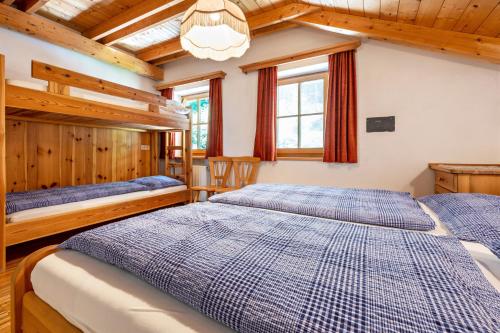 two beds in a bedroom with wooden walls at Lindenhof Apt 1 in Vandoies