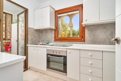 a kitchen with white cabinets and a window at Apartamento Ombú in La Herradura