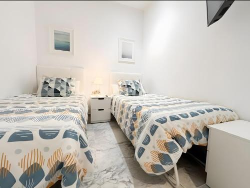 two beds in a room with white walls at Ola De Mar - Estepona in Estepona