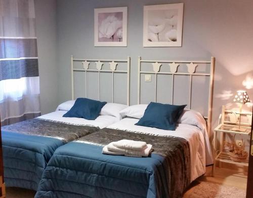 two beds with blue pillows in a bedroom at Casa rural El rincón de Gredos in Navaluenga