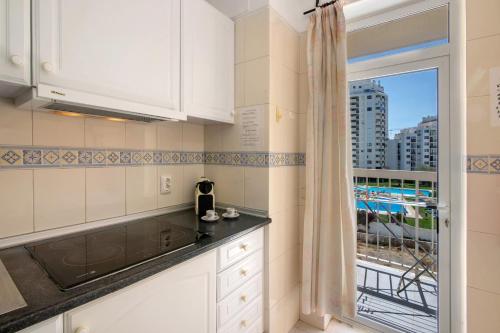 a kitchen with white cabinets and a window at Casa Néctar in Armação de Pêra