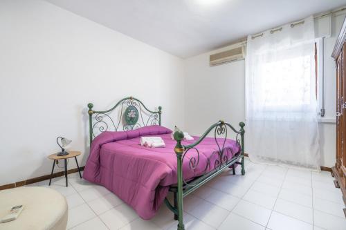 a bedroom with a pink bed with a purple blanket at Casa vacanze Elifra in San Giovanni Suergiu