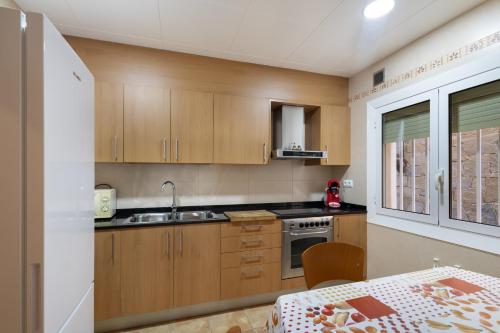 a kitchen with wooden cabinets and a table and a sink at Casa Menvil in Sant Jordi de Cercs