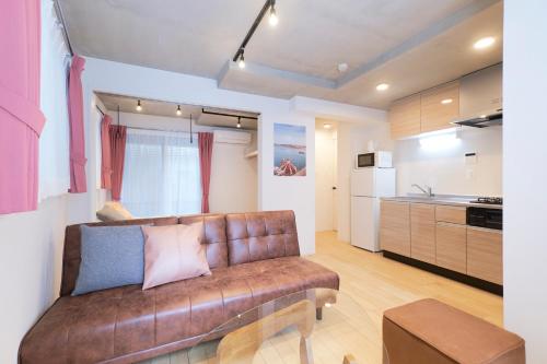 a living room with a brown couch in a kitchen at Frontier Comfort Kitaikebukuro by Tranova in Tokyo