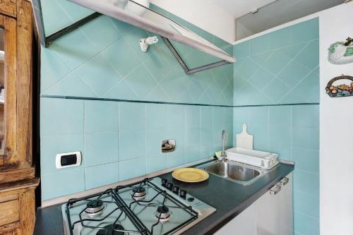a blue tiled kitchen with a stove and a sink at Casa Pepe in Imperia