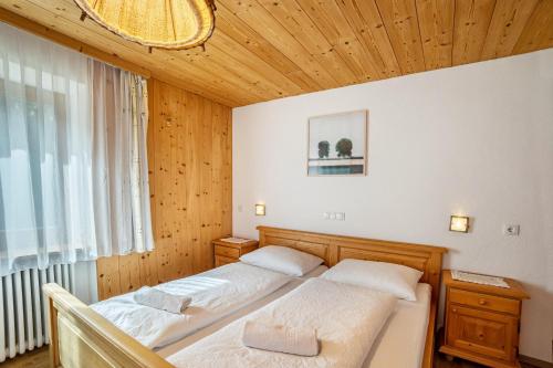 two beds in a bedroom with a wooden ceiling at Gartnerhof Apt Rose in Colle Isarco