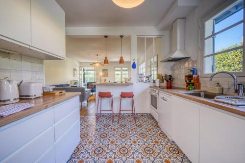 a kitchen with white cabinets and red stools at Maison Côté Bassin in Arcachon