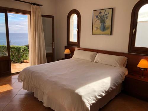 a bedroom with a bed with a view of the ocean at Villa Solymar in Cala Serena