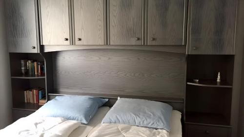 a bed with two pillows sitting under a wooden cabinet at Sommergarten mit Winternutzung in Karlshagen