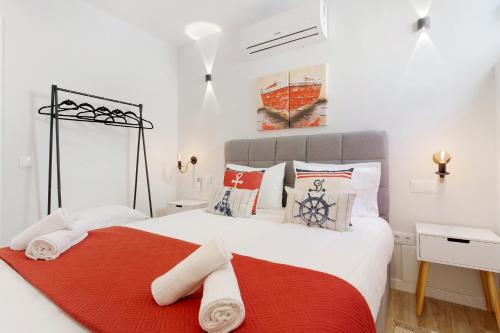 a white bedroom with a red and white bed at O Marinheiro 15B in Machico