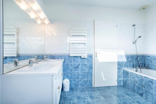 a blue tiled bathroom with a sink and a tub at Ty Bénodet - Maison de vacances in Bénodet