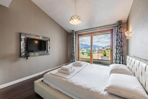 a bedroom with a bed and a tv and a window at Tranquility Villa with Pool Private Garden & BBQ by PikHost in Tirana