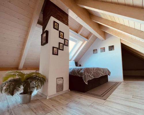 a bedroom in an attic with a bed and a plant at Ferienwohnung Allgäunest in Argenbühl